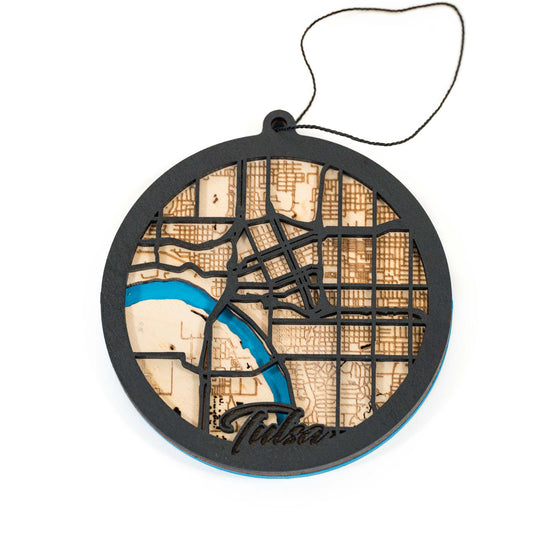 Round wooden ornament featuring a laser-cut map of Tulsa, Oklahoma, with detailed streets and a blue river accent.