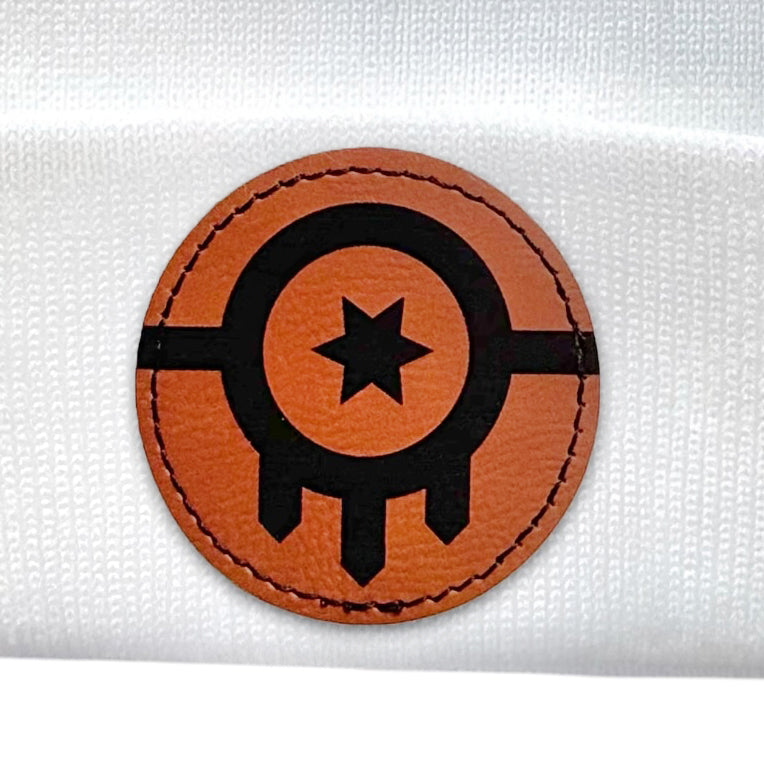 Close-up of the leather patch on a white beanie showcasing the Tulsa Flag design.